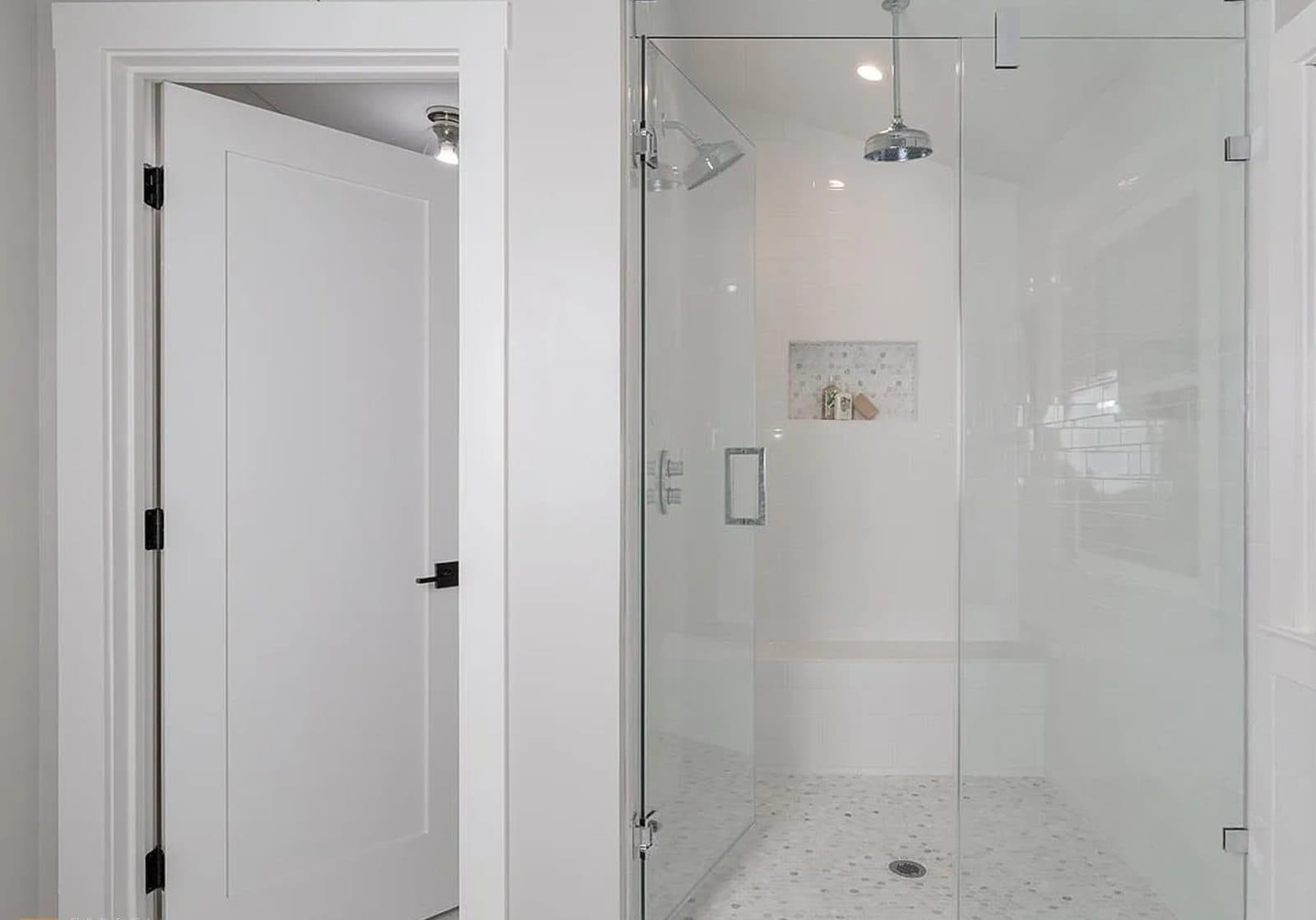 Frameless glass walk-in shower with subway tile, a tiled bench, mosaic niche and marble basketweave floor with a rainhead and wall shower